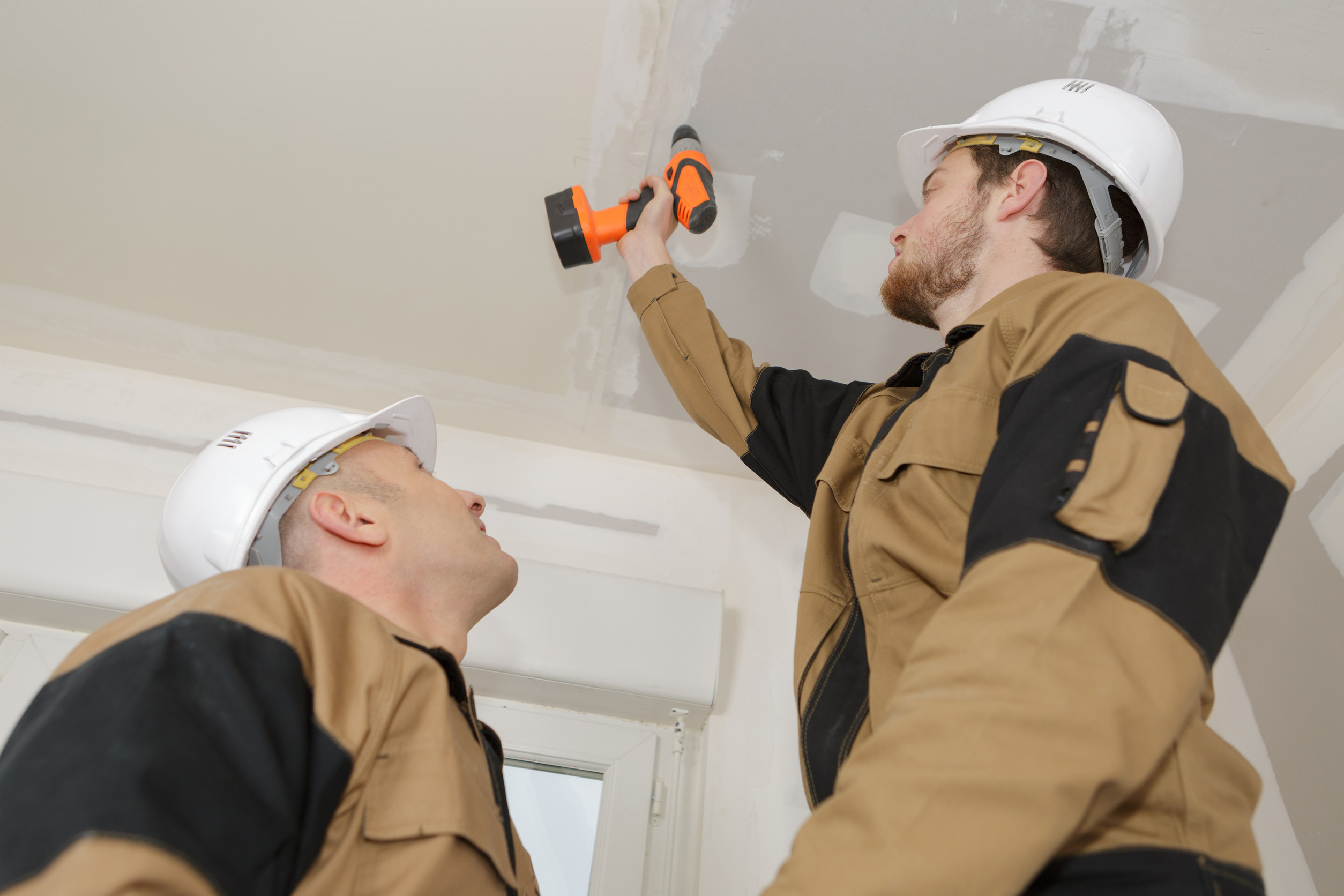 manual worker drilling ceiling with a drilling machine